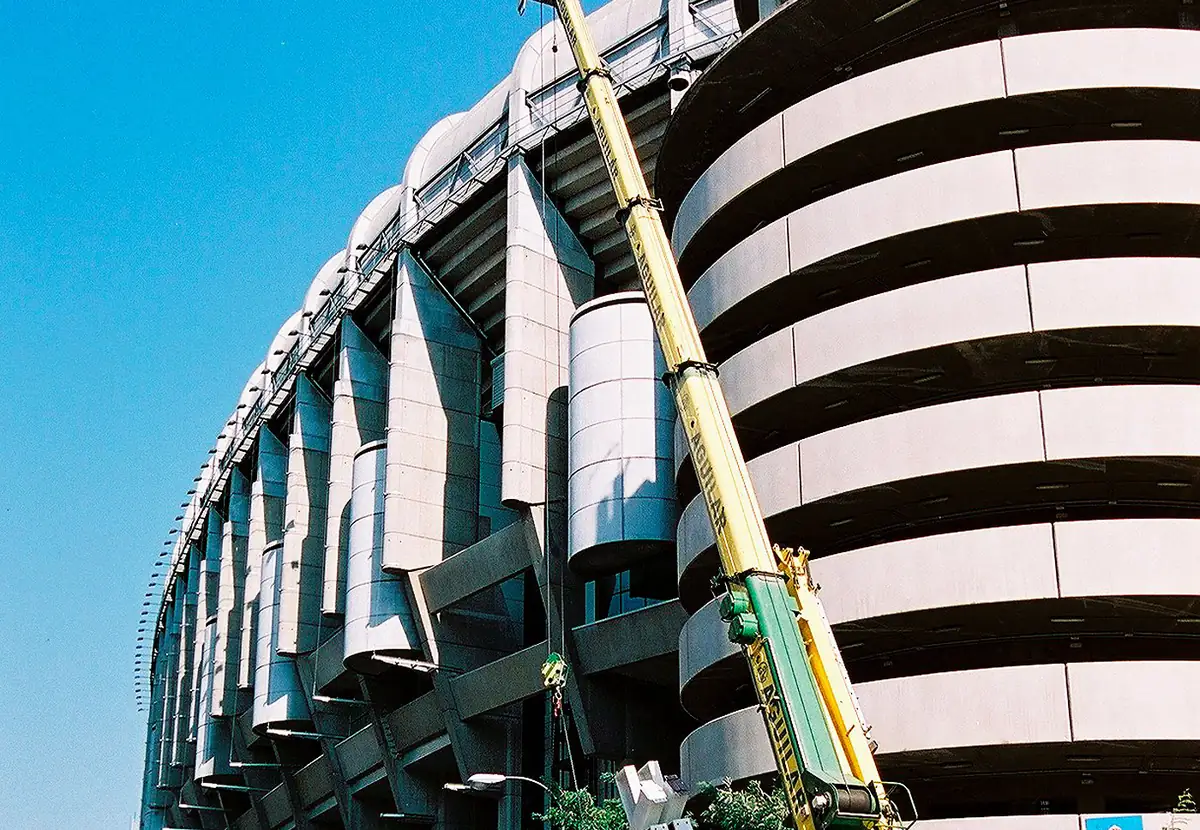 Grúa de celosía sobre cadenas junto a un estadio
