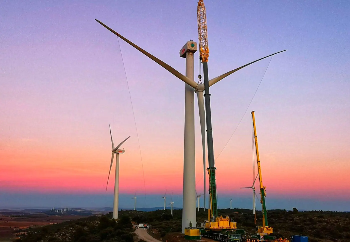 Grúa de Aguilar Wind montando un aerogenerador al atardecer