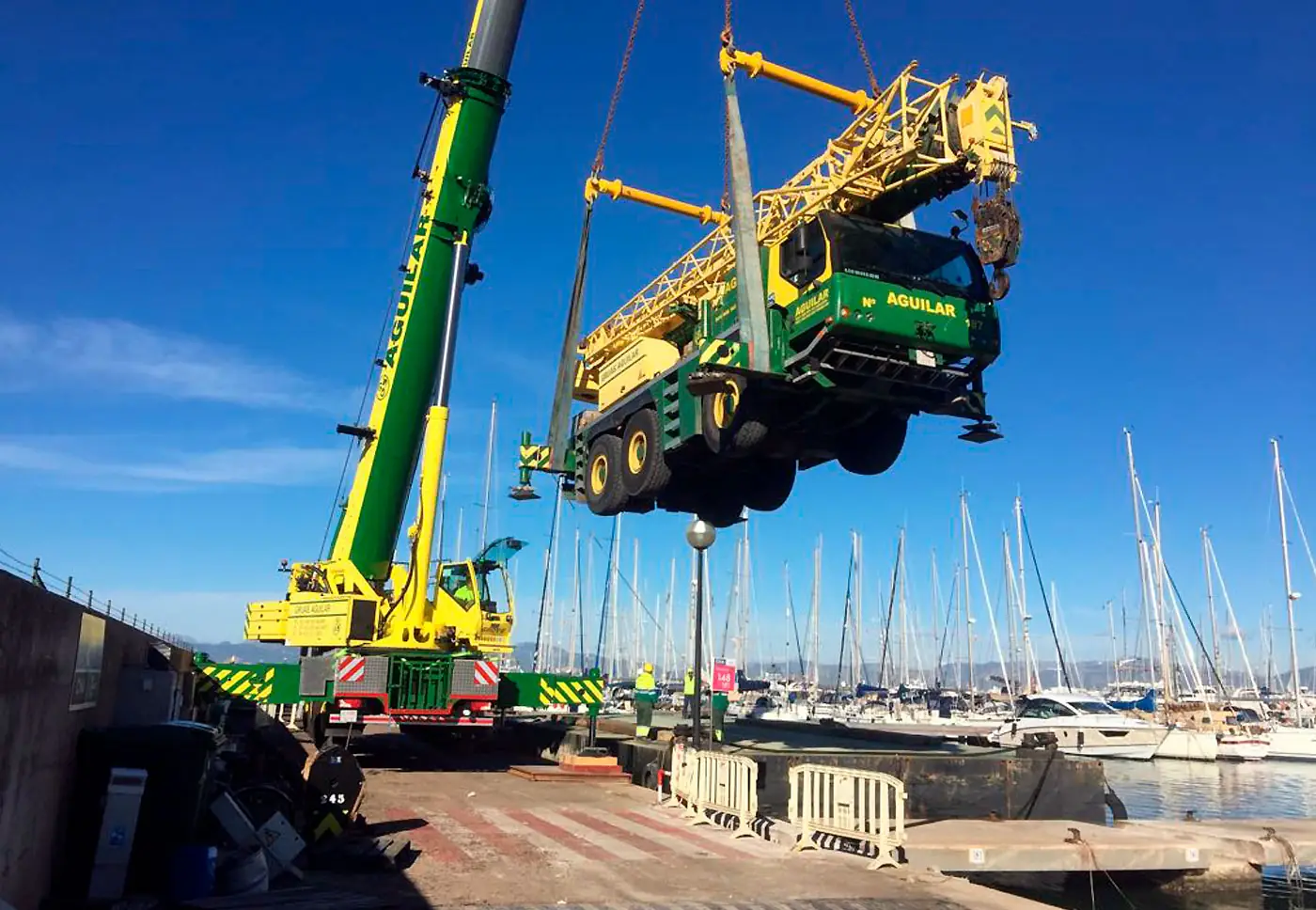 Grúa móvil elevando una grúa en un puerto deportivo